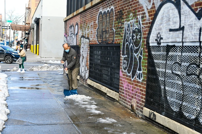 a man with his arm up leaning against the side of a building