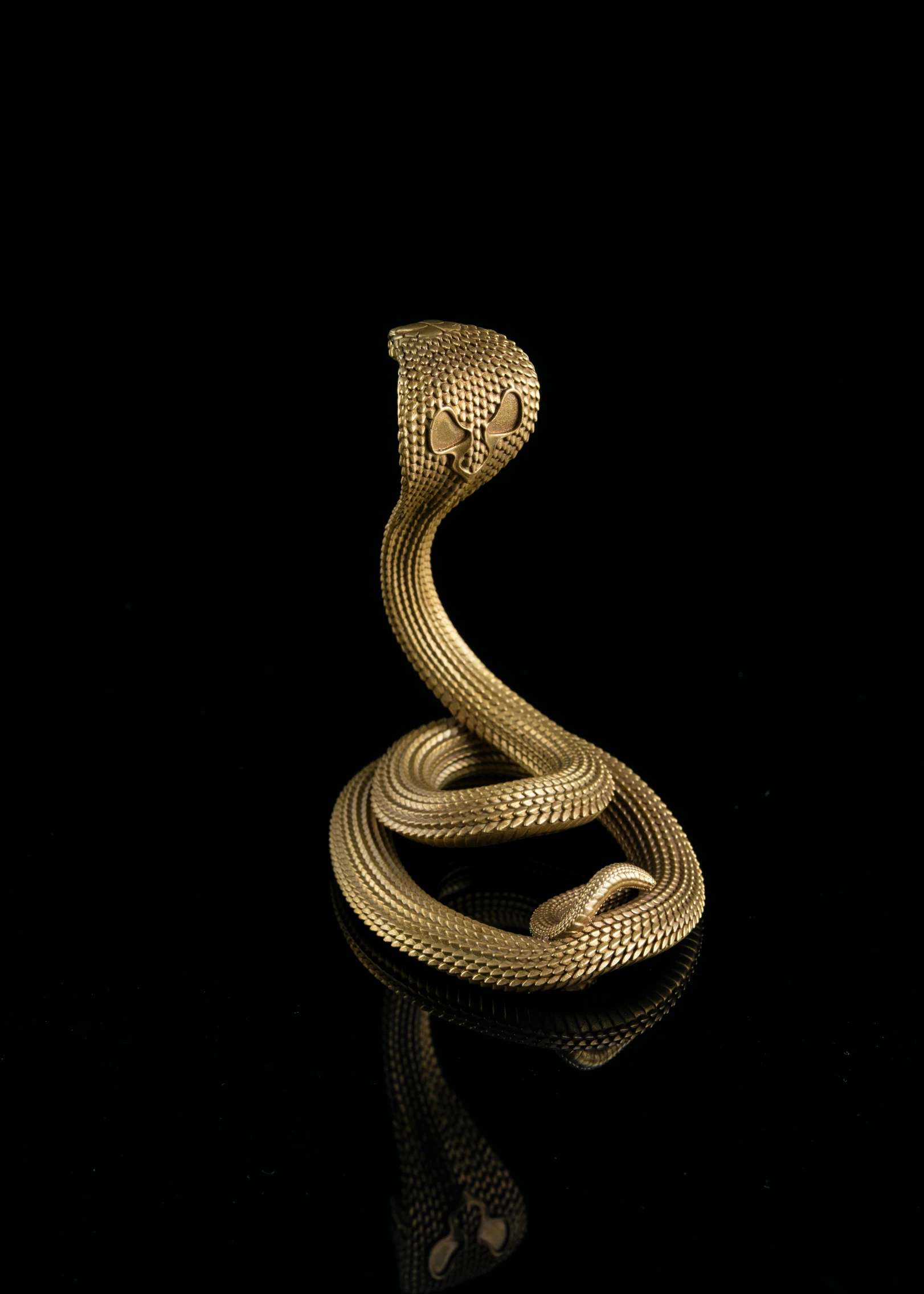 a gold snake statue against a black background