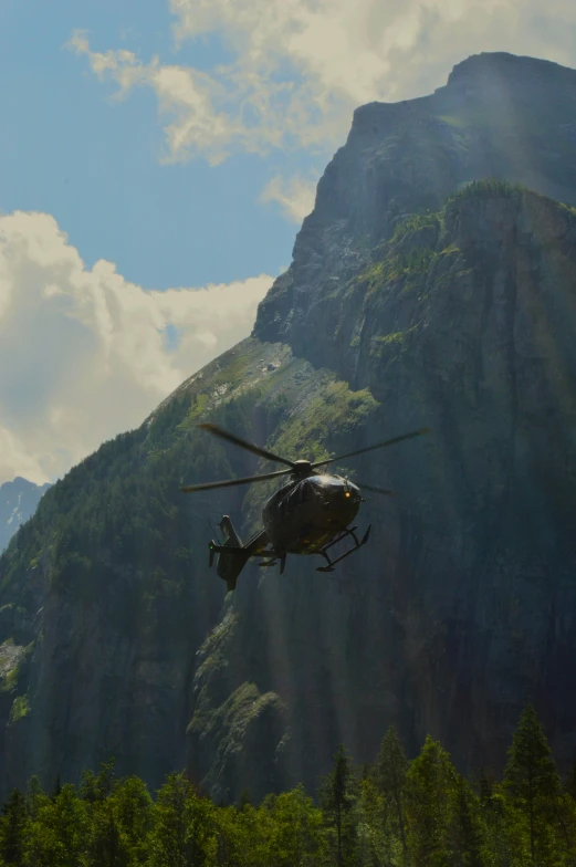 a helicopter hovers close to the top of a mountain