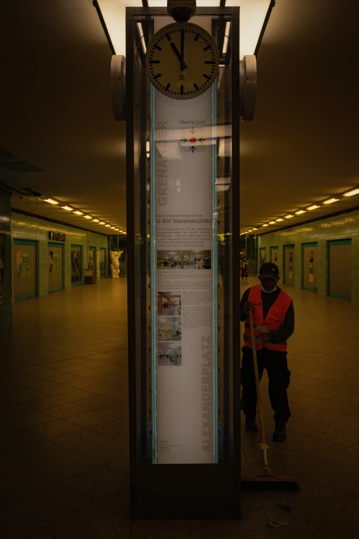 two people standing by a big clock in a room