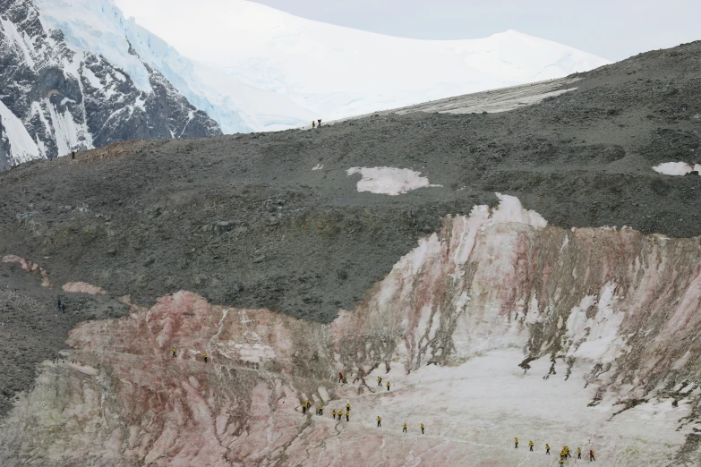 a group of people walking up the side of a snow covered mountain