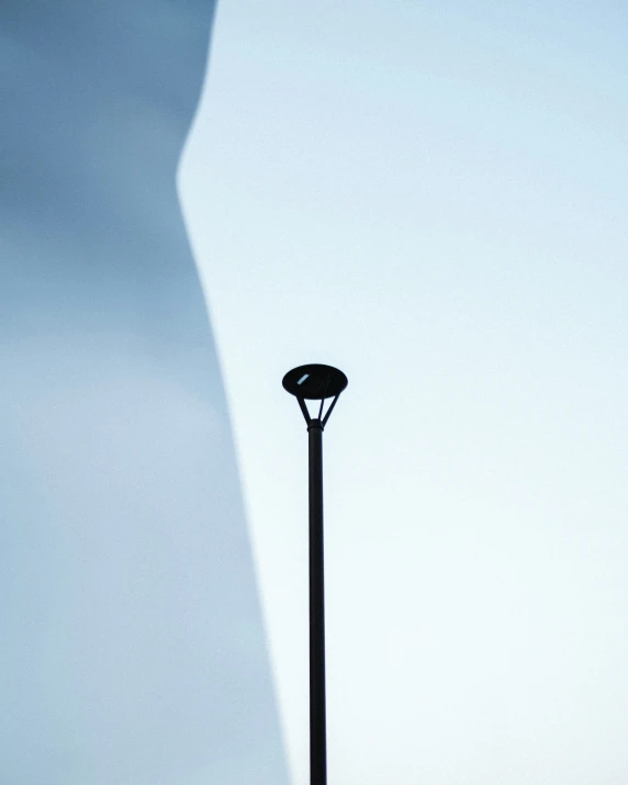a close up view of a street light in front of a long shadow