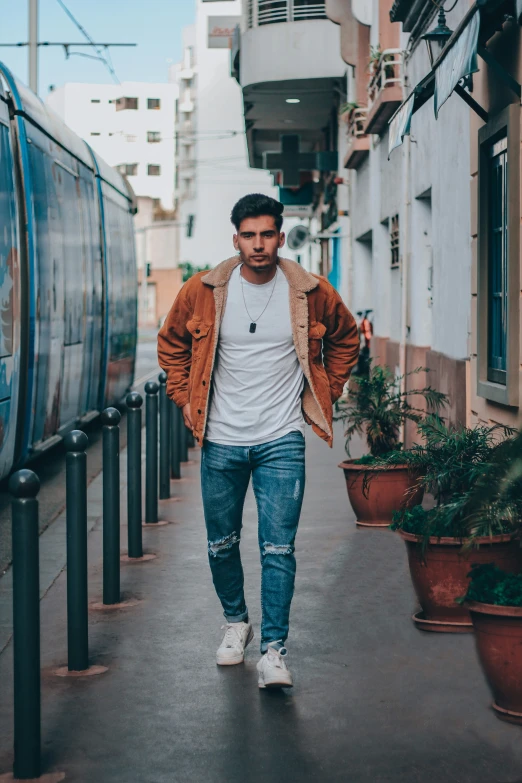 the man walks along an alley way near some potted plants