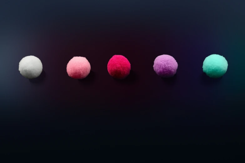 colorful cotton balls arranged in different colors on a black surface