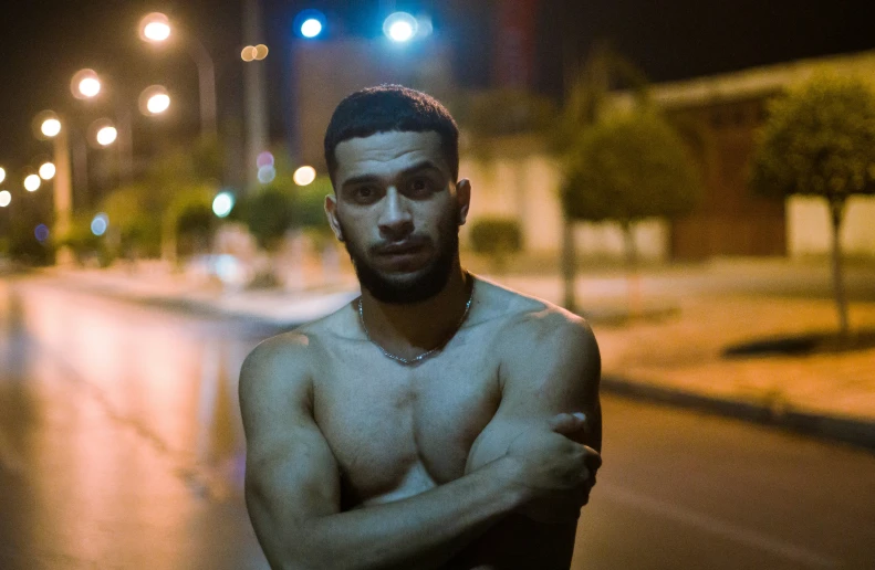 shirtless man leaning against the street while waiting at the light