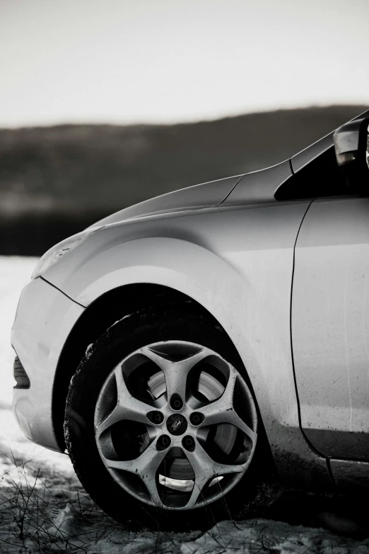 a white car parked on the side of a snow covered street