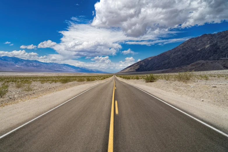 an empty road stretches in the distance along a mountain range