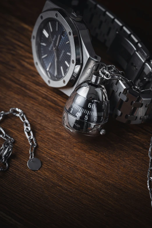 two watches are being  to chains and are on a wooden table