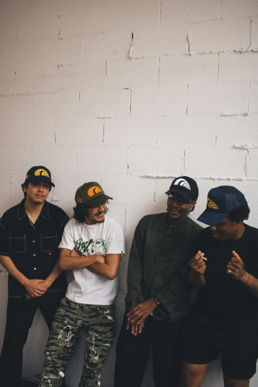 a group of young men standing next to a white wall