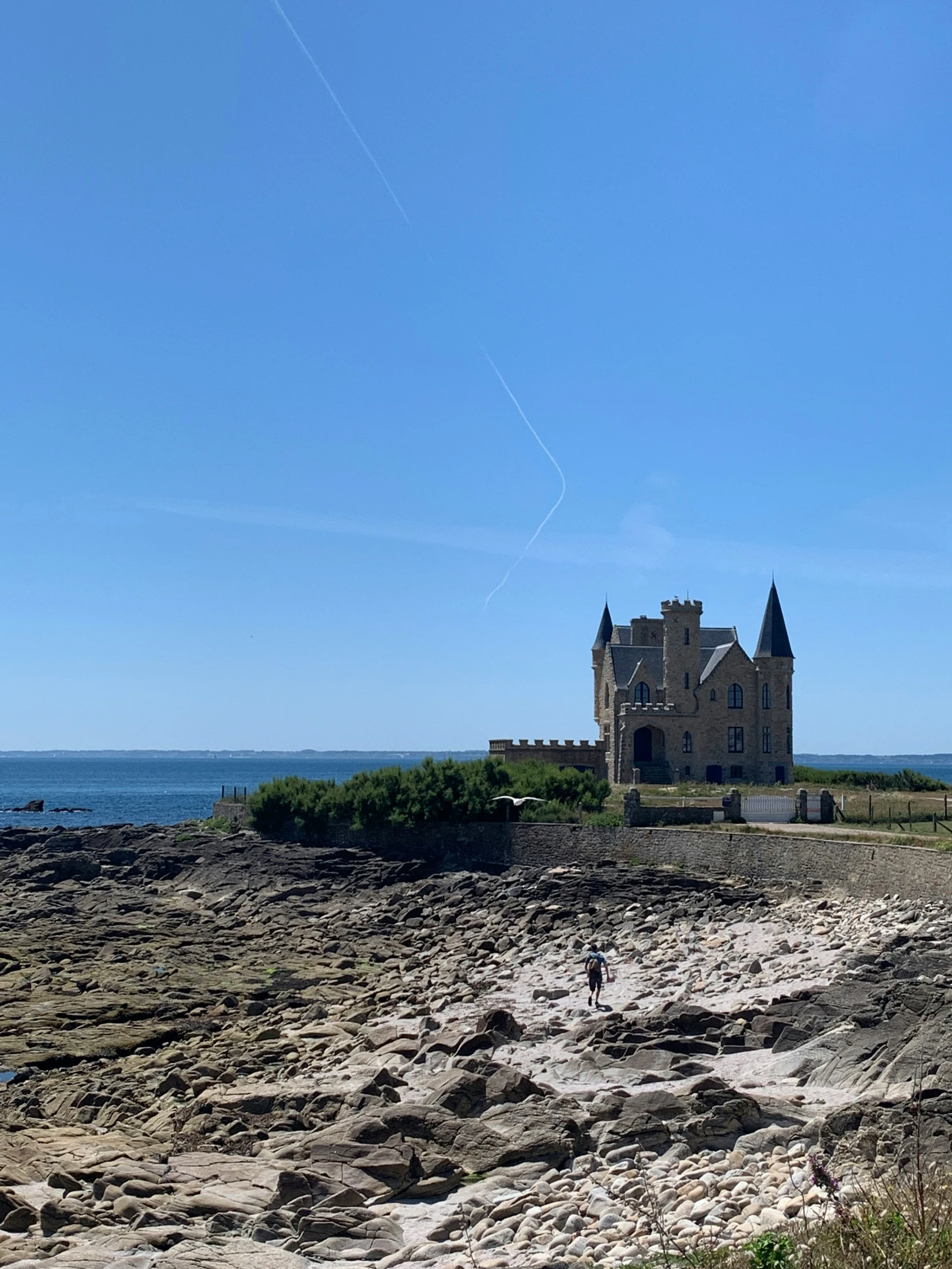 a man flies a kite on a beach near an old building