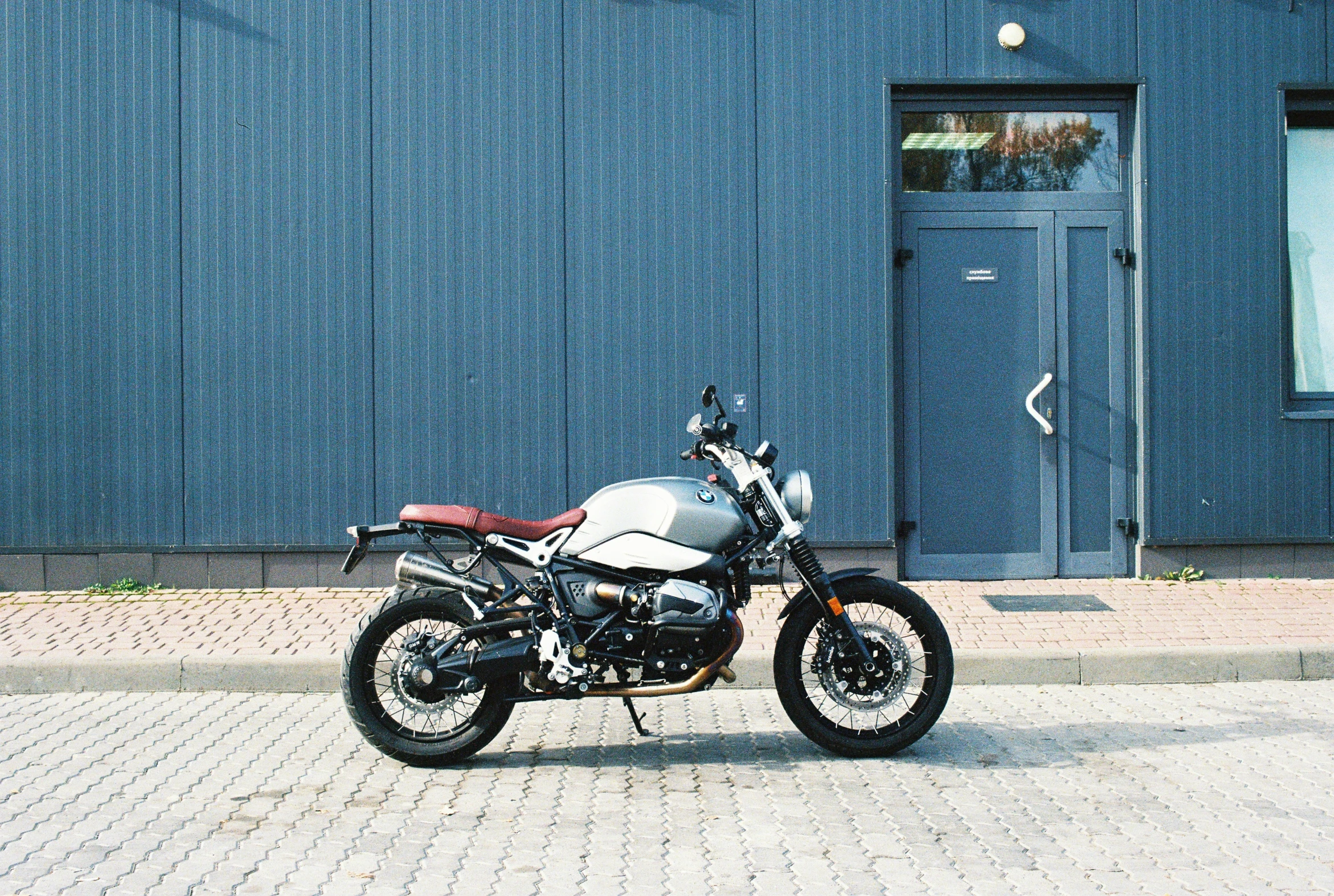 a motorcycle sitting on the street next to blue building