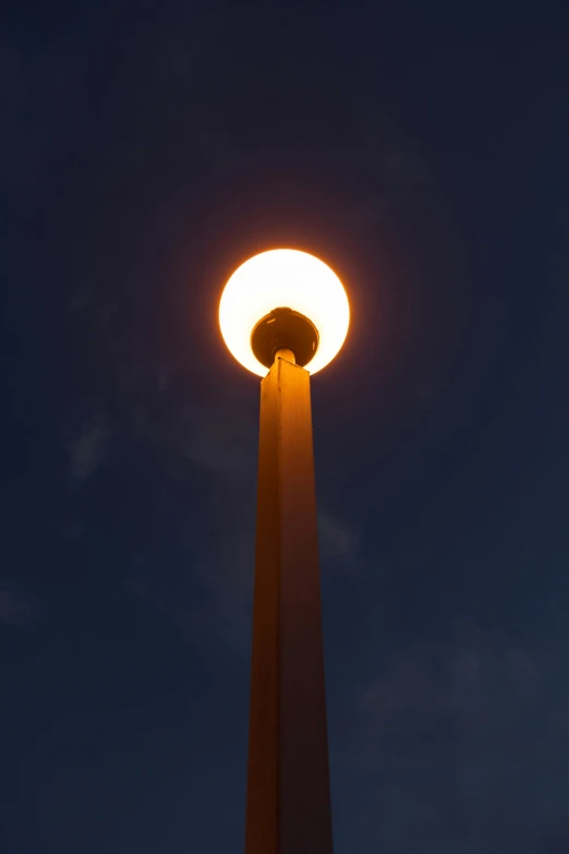 the light is illuminating on the pole that holds the clock