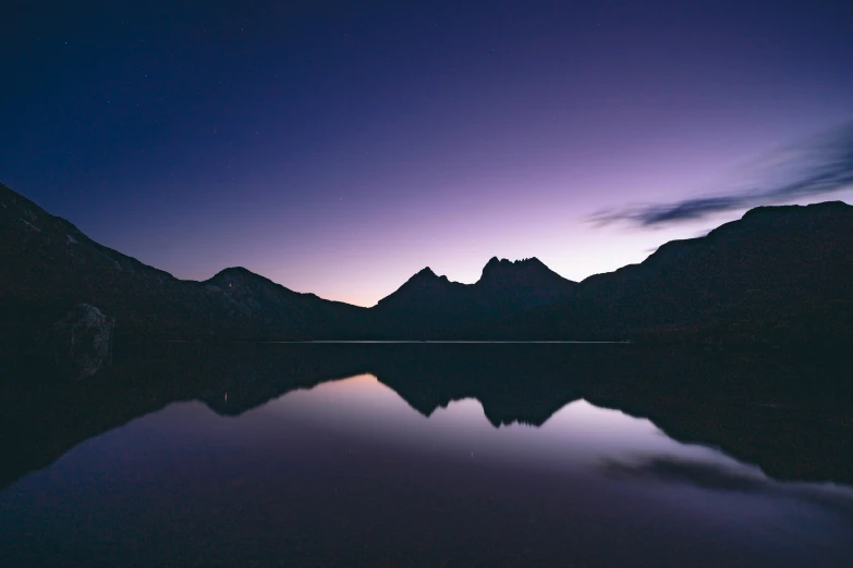 a purple and black sky with some mountains