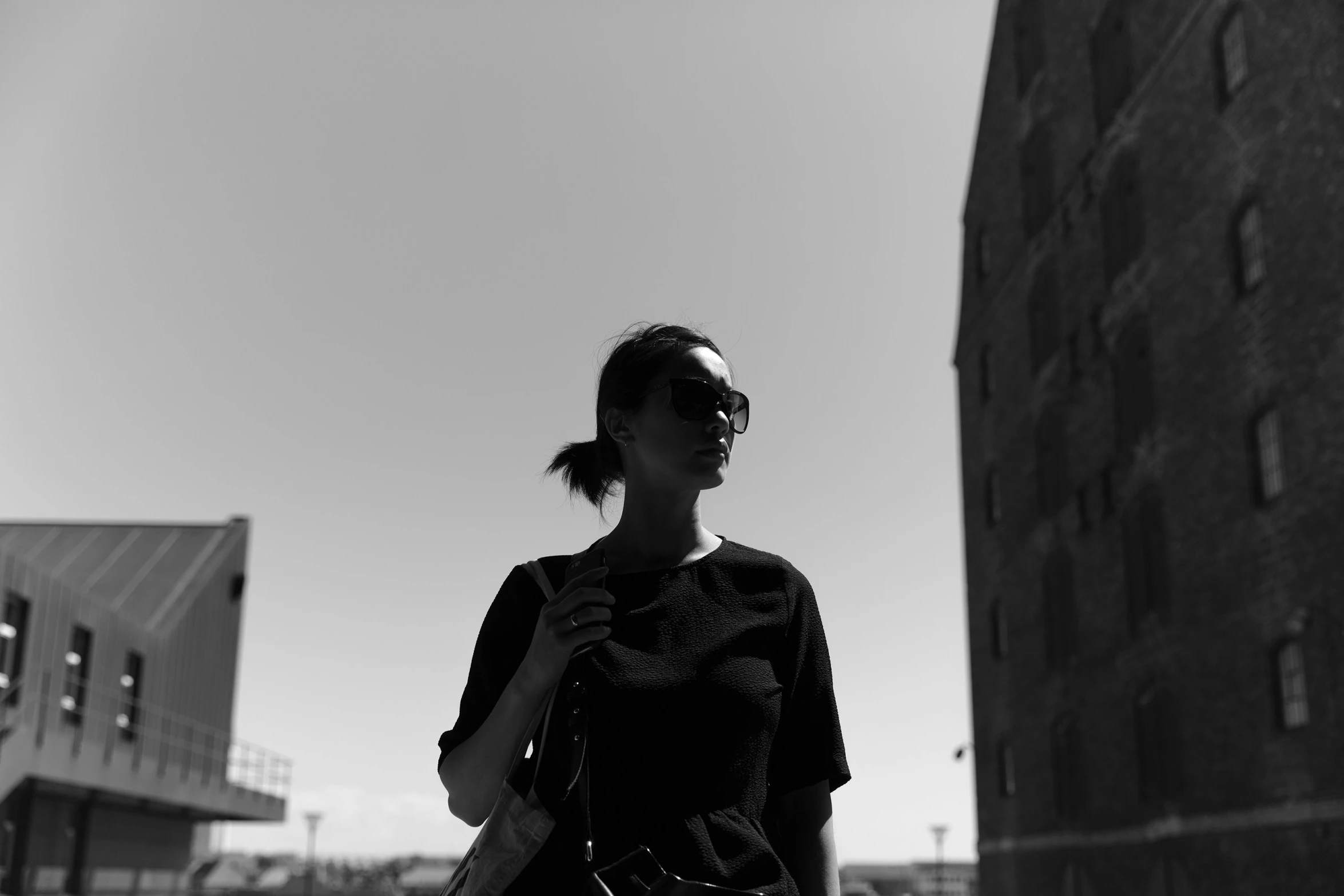 a woman standing outside, holding her purse