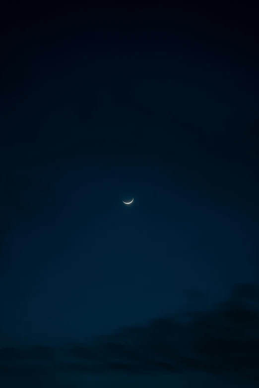 a dark picture shows the moon rising with only a few clouds