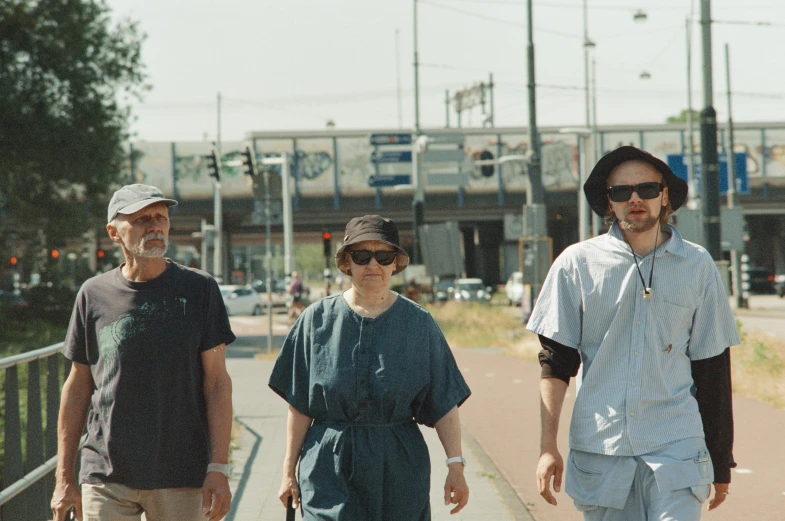 three people with walking stick walk down a side walk