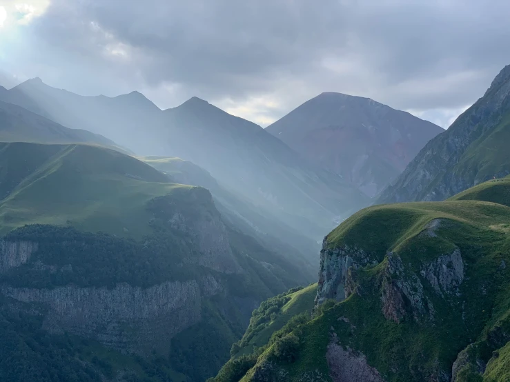 a valley filled with tall green mountains on the side of a mountain