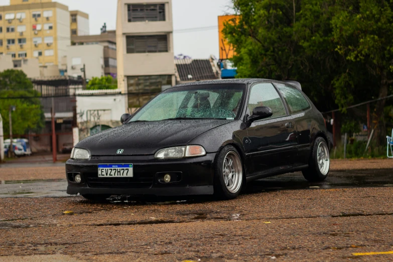 a black compact car parked in front of tall buildings