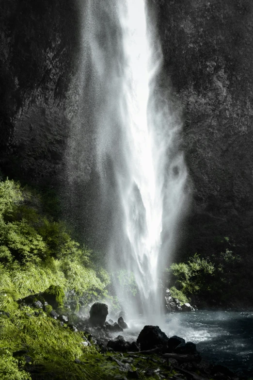 a waterfall spilling into the sky surrounded by green vegetation