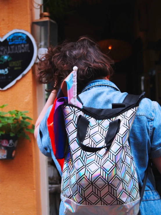 a woman wearing a holographic backpack walking away