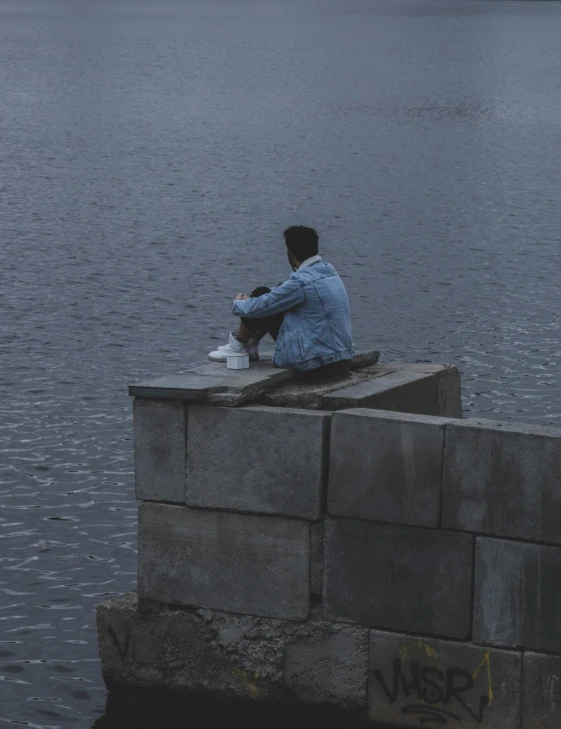 a person sitting on a wall by some water