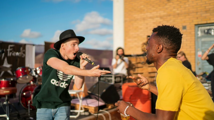 two people, one in yellow and the other black, are singing and playing music on stage