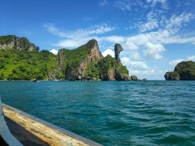 a long boat traveling past small island type rock formation