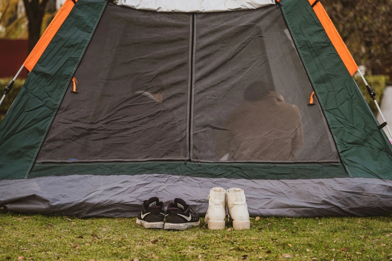 there is a tent in the grass with shoes underneath it