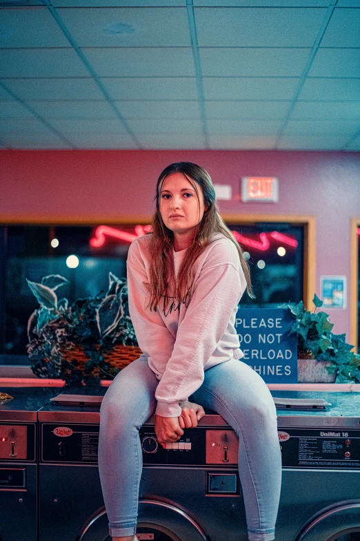 a girl in white sweater sitting on a washer