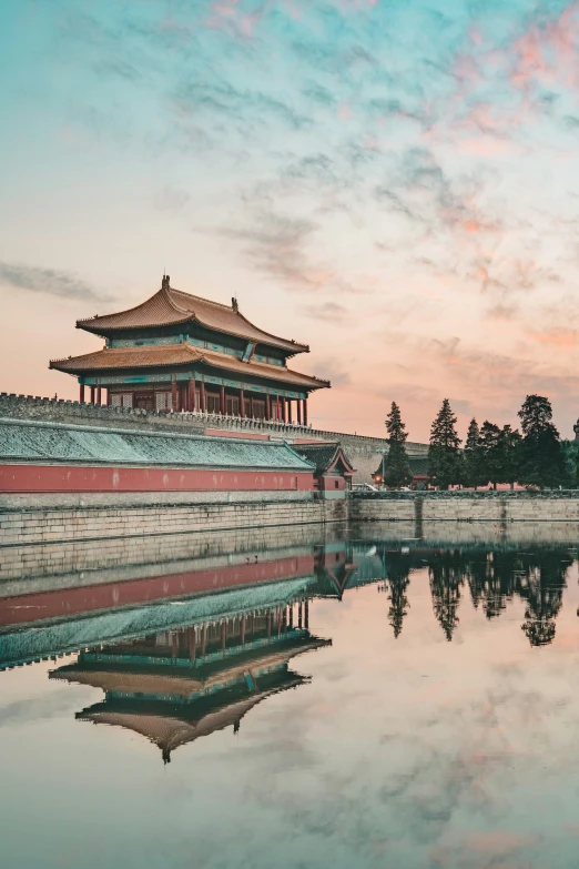 the sun sets behind a tower with a chinese temple in the foreground