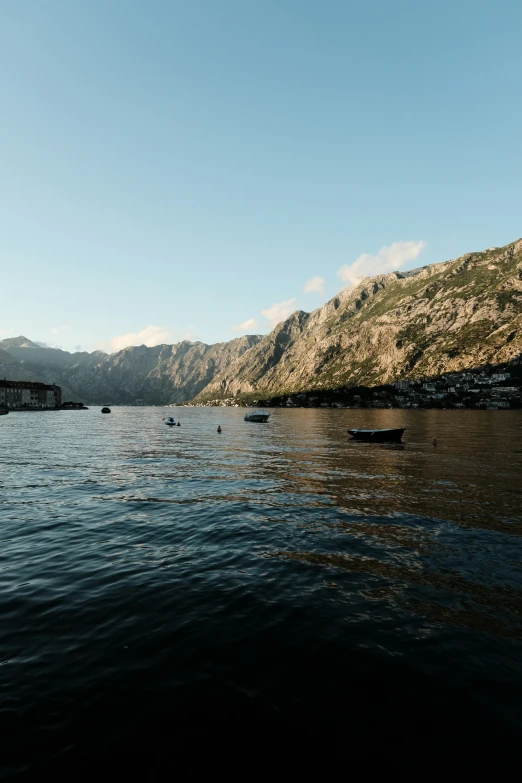 a body of water with rocks on the side and hills in the background