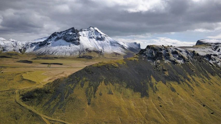 a group of snow capped mountains with grass growing all around