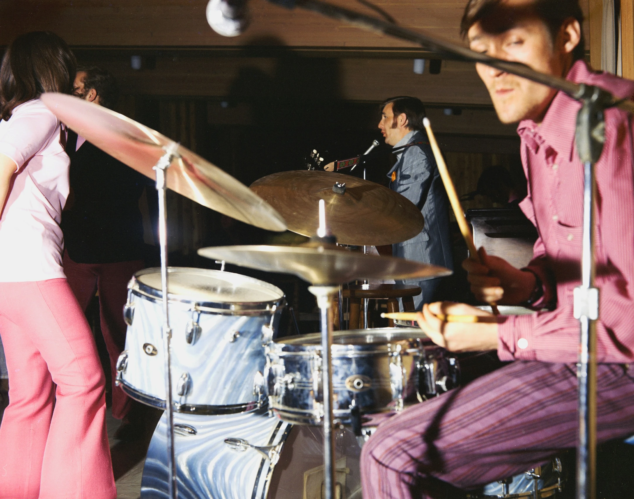 two musicians playing drums in front of a woman