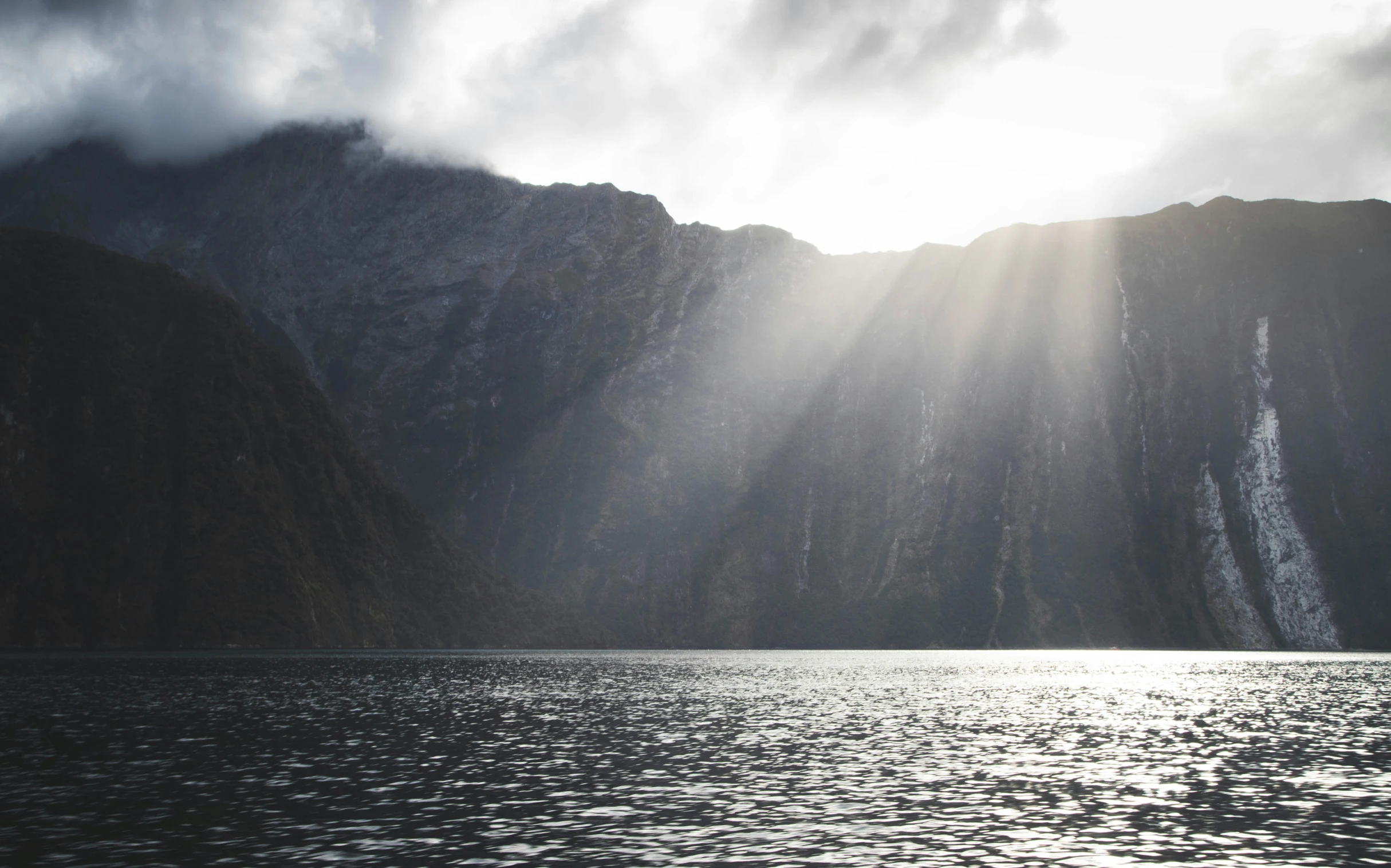 the sun is breaking through the clouds over the water