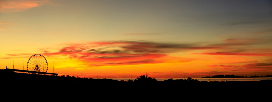 a very bright sunset behind an amut park rides