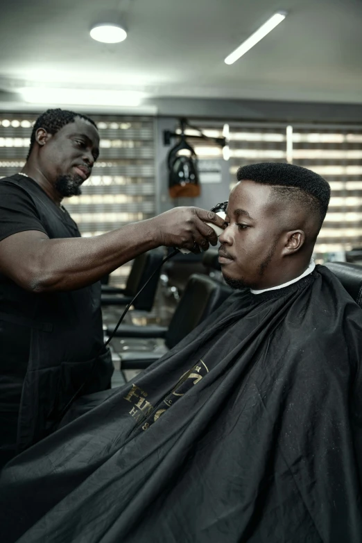 a black man sitting in a hair salon  another mans hair