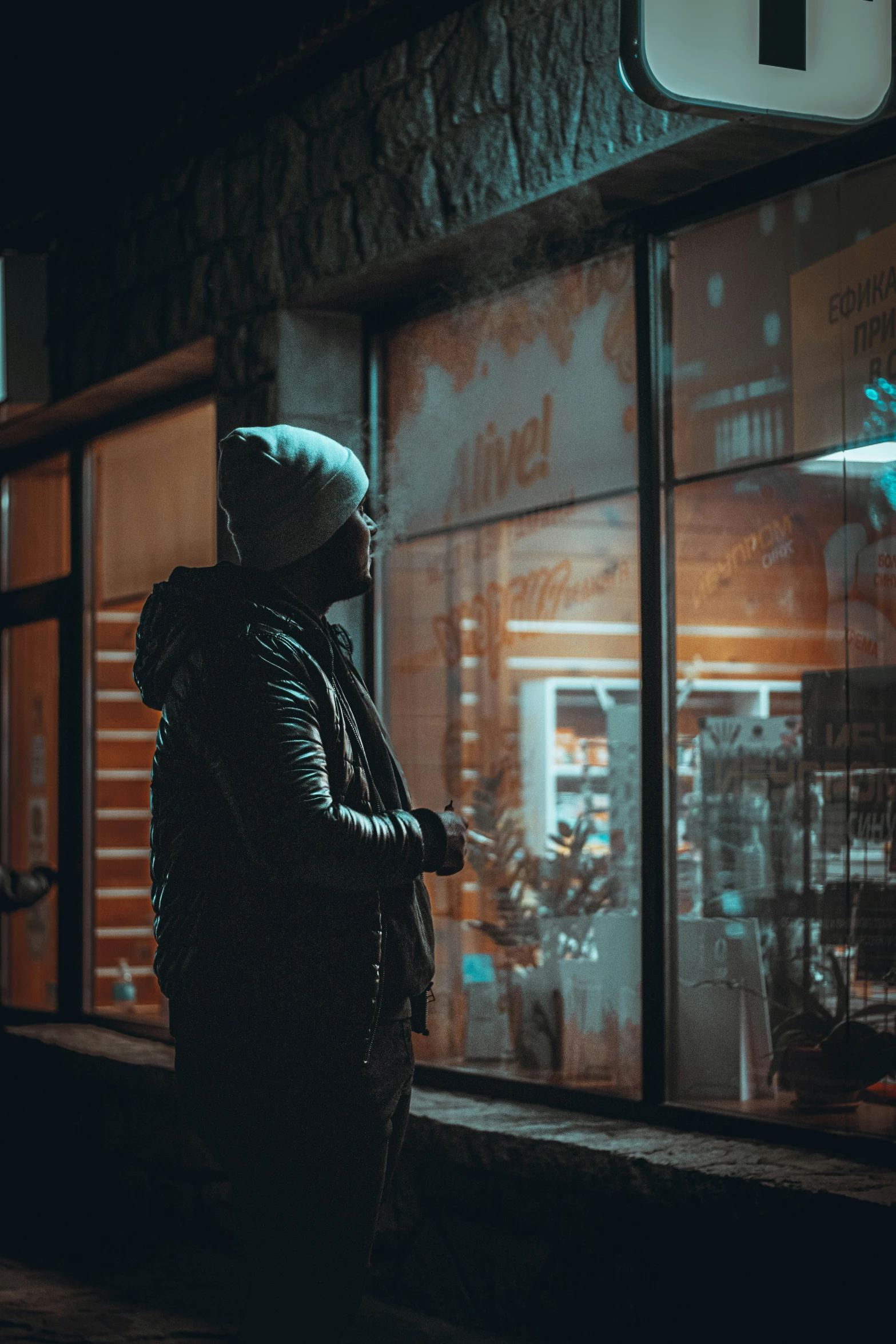 a person wearing a hooded coat standing outside a building