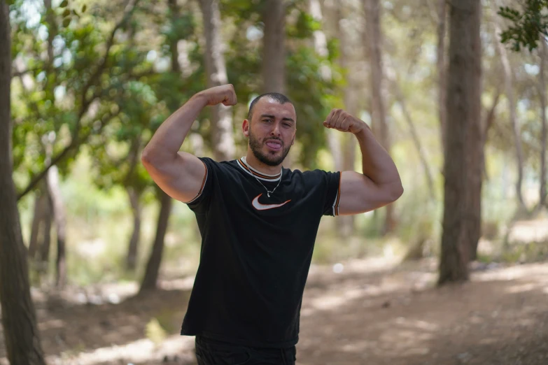 a man is standing in a wooded area with arms spread