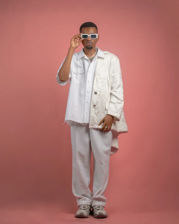 a man in a white suit and sunglasses holding a pair of sunglasses