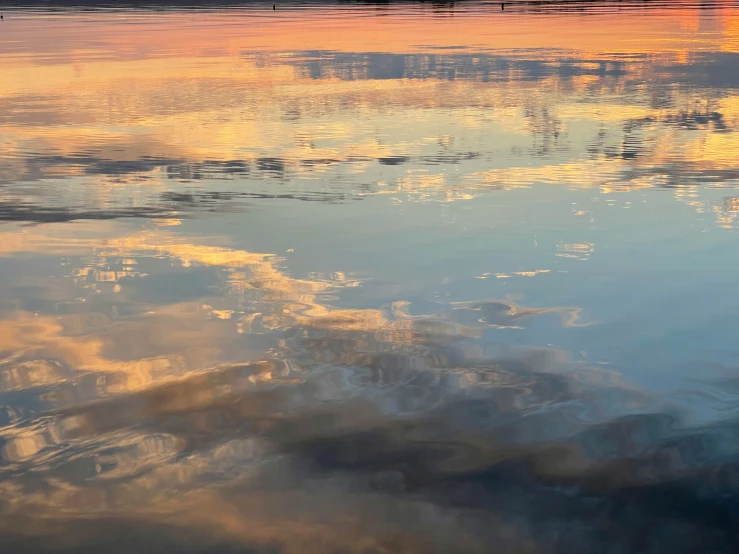 a large body of water with boats and sky reflection in it