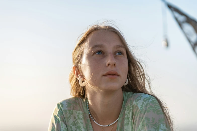 a woman in a green and white blouse staring off into the distance