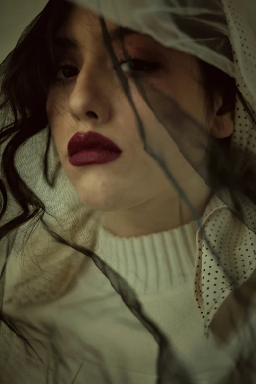 woman with veil, red lips and dark eyes staring in front of camera