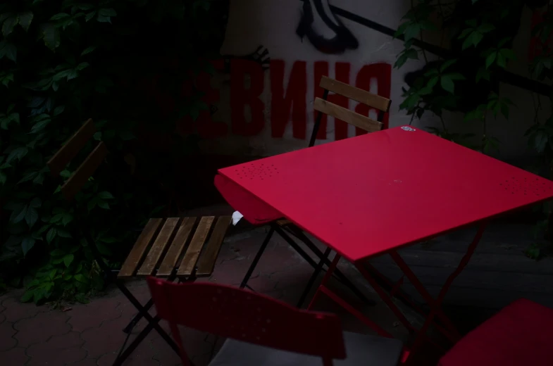 red table and chairs next to wall with graffiti on it