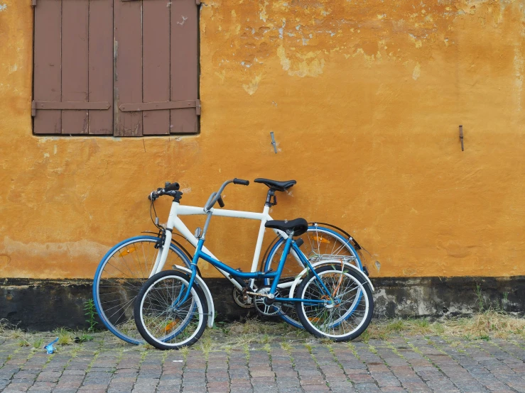 two blue and white bikes against an orange wall