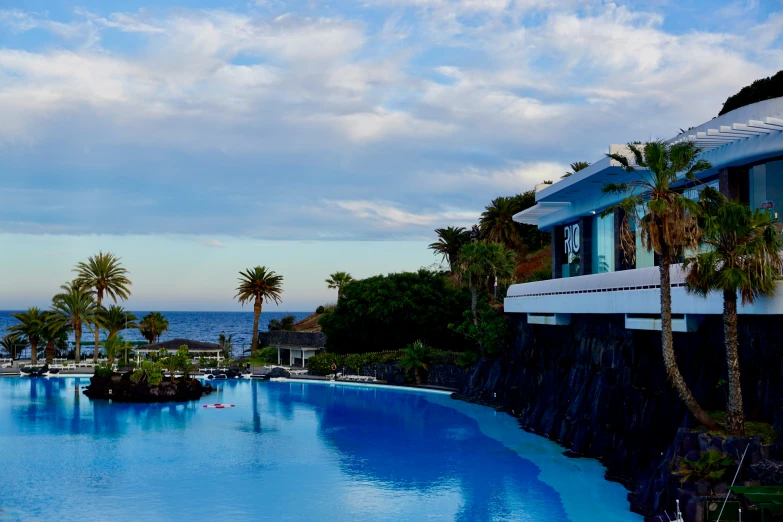 some very large blue swimming pool next to the beach