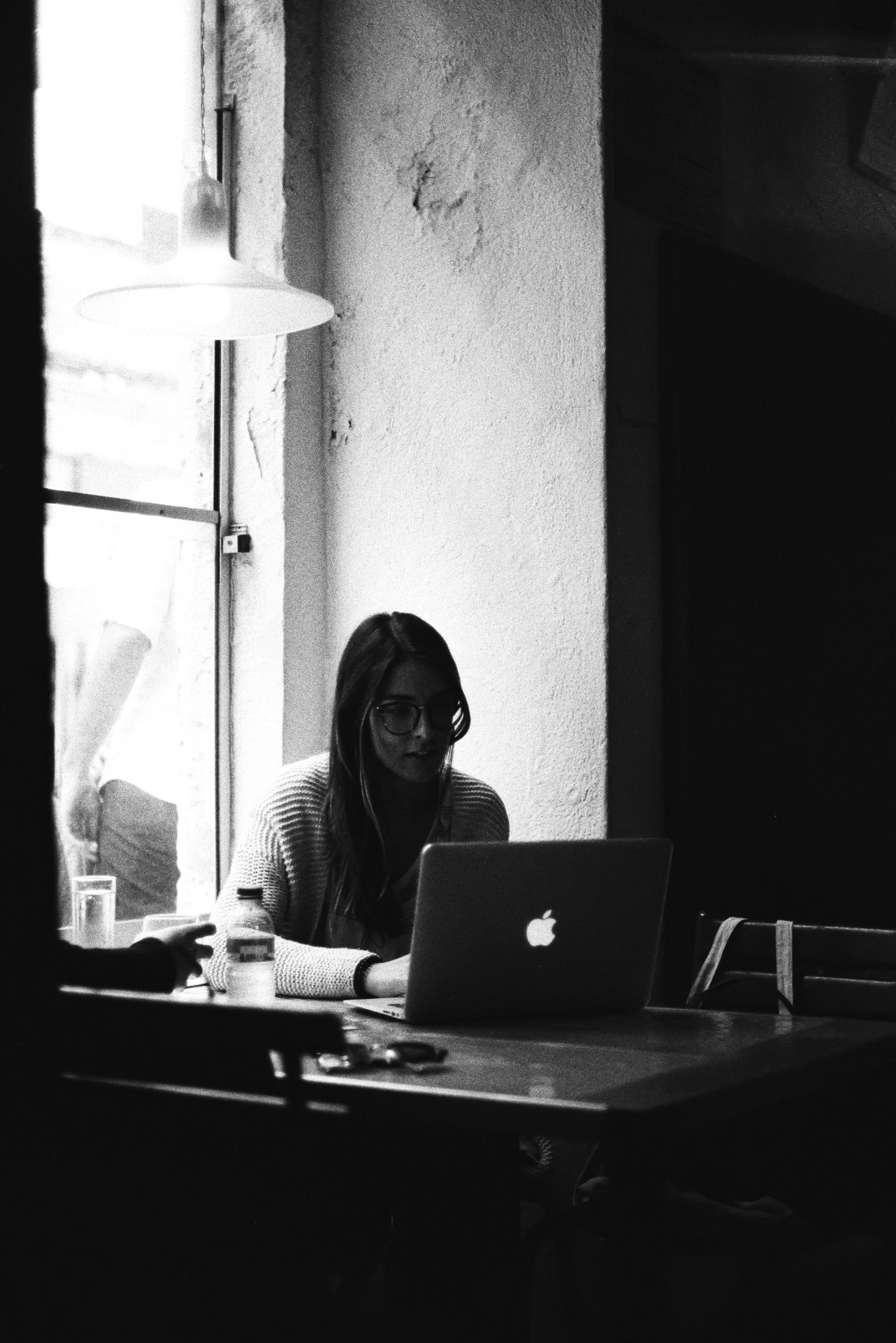 black and white image of a person using a laptop at a desk