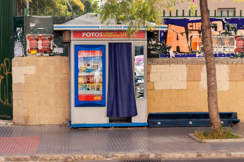 a small blue and white ticket booth sitting on the side of a street