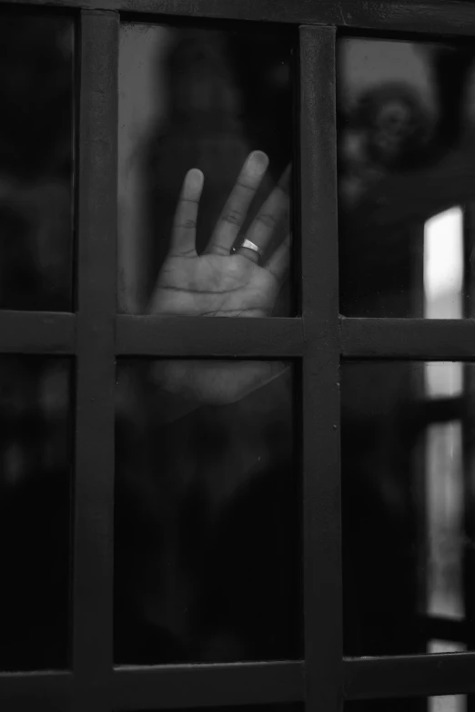 a hand on a window glass is making the vulcan shape