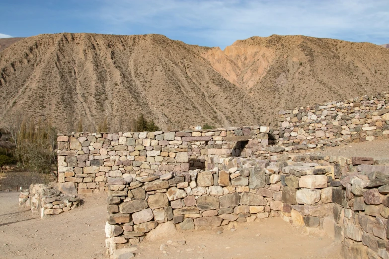 an ancient house with a rocky wall in the desert