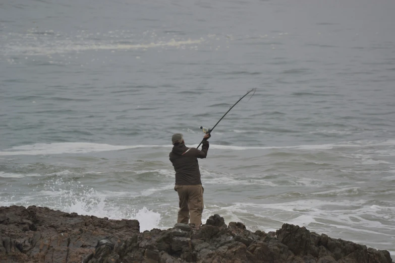 a man fishing on the beach with choppy waters
